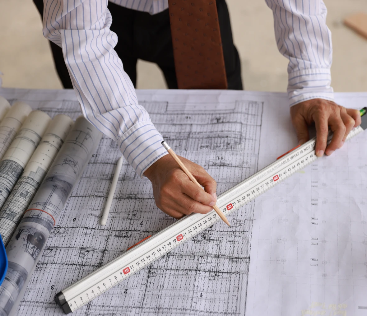 Engineer measuring plans with scale and pencil